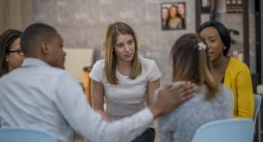 Man touching woman's shoulder in a meeting setting